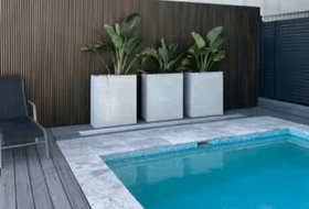 A Newtechwood castellation privacy screen In the Aged Wood colour is a perfect complement to this sparkling pool