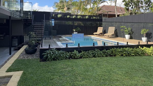 Backyard deck with composite decking and glass pool balustrade by UrbanArch Building in Sydney